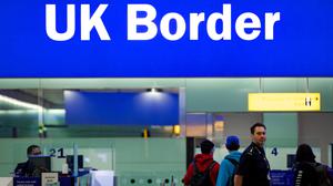 Grenzbeamte stehen am Flughafen London-Heathrow unter einem Schild mit der Aufschrift „UK Border“ (Grenze des Vereinigten Königreiches).