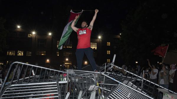 Ein Student der George Washington University schwenkt eine palästinensische Flagge, während er auf einer Polizeisperre steht.
