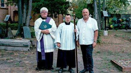 Pfarrer Olaf Tuszewski steht mit Georg Mesus und dessen Sohn Johannes (v.l.) auf dem Domfriedhof der St.-Hedwig-Gemeinde.