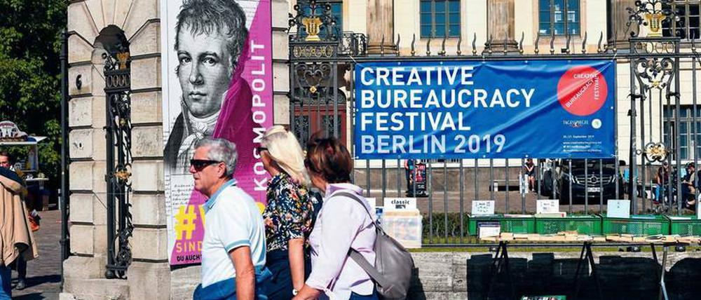 Pasanten gehen an der Humboldt-Universität vorbei und an den Plakaten für das Creative Bureaucracy Festival.