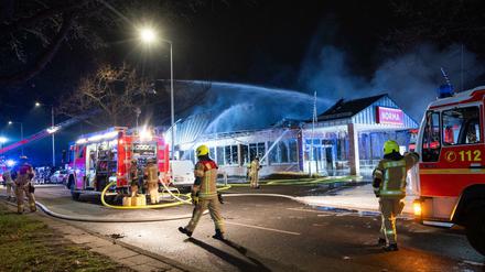 Feuerwehrleute löschen am Neujahrsmorgen einen brennenden Supermarkt in Buckow.