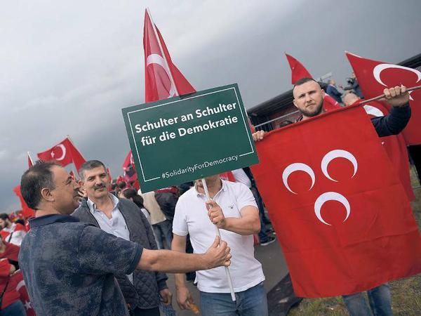 Recht extrem. An der Kundgebung nehmen auch türkische Nationalisten teil, das Erkennungsmerkmal der „Grauen Wölfe“ sind die drei Halbmonde auf rotem Grund.