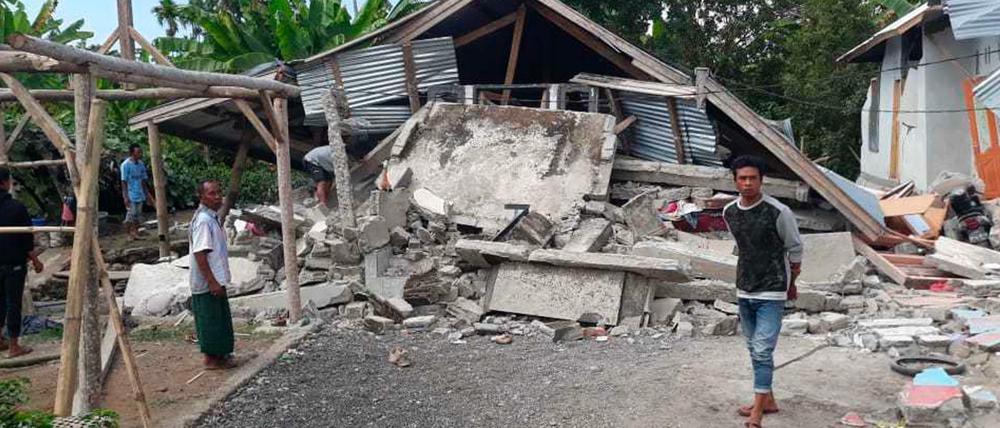 Bewohner gehen an Häusern vorbei, die durch ein Erdbeben beschädigt wurden.
