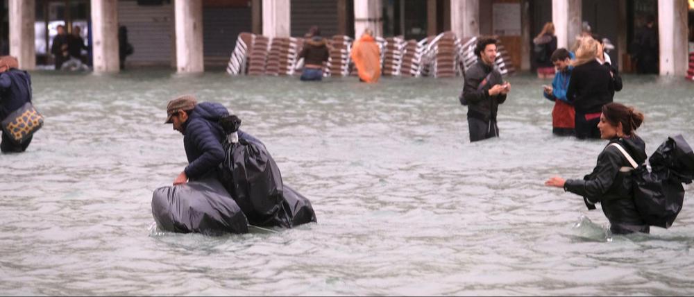 Menschen versuchen, durch das Wasser den Markus-Platz zu überqueren.