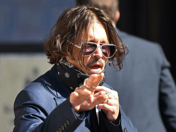 Vor dem Londoner Gericht nimmt Johnny Depp seine Maske ab.
