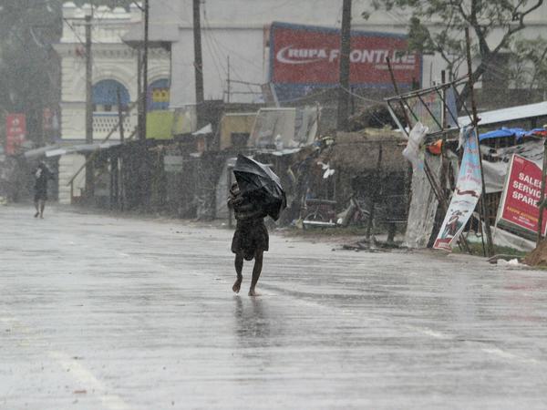 Menschen schützen sich mit Regenschirmen im ostindischen Bundesstaat Orissa vor Regen des Zyklons.