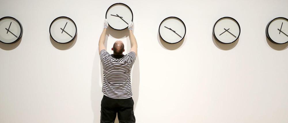 Ein Mitarbeiter wechselt in einer Ausstellung in der Talbot Rice Gallery eine Uhr aus.
