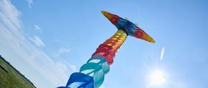 Auf dem Tempelhofer Feld startet ein langer bunter Drachen beim 10. Festival der Riesendrachen am spätsommerlich blauen Himmel der Sonne entgegen.