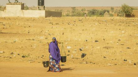 Eine Frau trägt zwei Wassereimer.