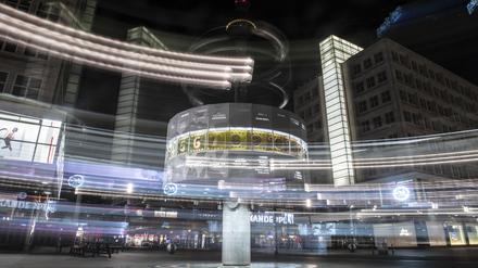 Bunte Lichtstreifen rahmen die Weltzeituhr auf dem Alexanderplatz in der Nacht ein.