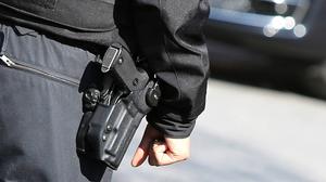 Ein Polizist von hinten mit einer Schusswaffe. (Symbolbild)