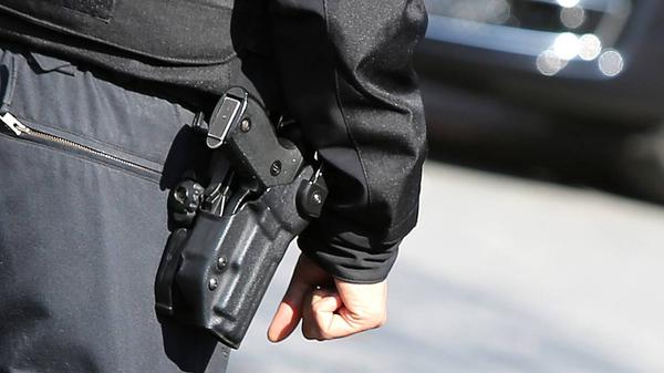 Ein Polizist von hinten mit einer Schusswaffe. (Symbolbild)