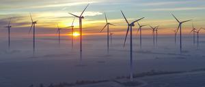 Hinter Wolkenschleiern geht in Brandenburg die Sonne über dem Windenergiepark Odervorland auf.
