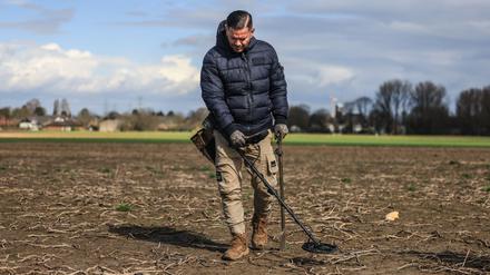 Moderne Schatzsuche. Profi-Sondengänger Carsten Konze läuft mit seinem Detektor über ein Feld.