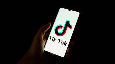 This photograph taken on April 19, 2024 shows a man holding a smartphone displaying the logo of Chinese social media platform Tiktok in an office in Paris (Photo by Antonin UTZ / AFP)