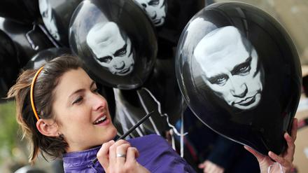 Anna Büchling zersticht am Donnerstag (26.04.2012) vor der russischen Botschaft in Berlin einen Luftballon mit dem Bild von Putin. In den Ballons befinden sich Zettel mit einer Petition an Wladimir Putin, mit der Aufforderung eine freie Berichterstattung in seinem Land zuzulassen. Foto: Hannibal dpa/lbn ++ +++ dpa-Bildfunk +++