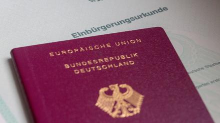 Eine Einbürgerungsurkunde der Bundesrepublik Deutschland und ein deutscher Reisepass liegen auf einem Tisch. (Symbolfoto)
