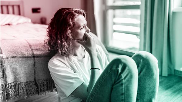 Eine Frau sitzt zweifelnd in ihrem Schlafzimmer (Symbolbild).
