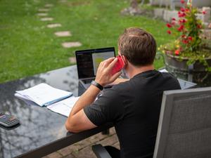 Ein Mann sitzt im Garten und arbeitet am Laptop (Symbolbild).