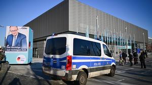 Polizei steht während des 37. Bundesparteitag der CDU im CityCube Berlin am Eingang neben einem Plakat von CDU-Kanzlerkandidat Merz.