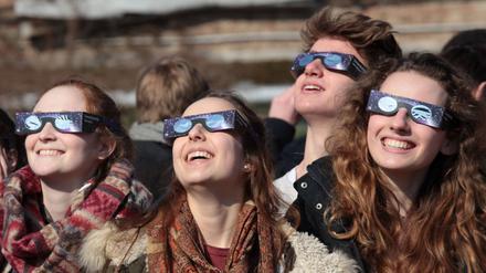 Junge Menschen betrachten eine Sonnenfinsternis 2015 in Potsdam.