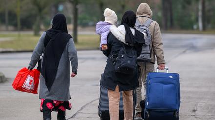Migranten verlassen mit Reisegepäck das Gelände der Zentralen Ausländerbehörde Brandenburgs (ZABH). Brandenburg geht einen neuen Weg für schnellere Rückführungen von Asylbewerbern nach Polen.