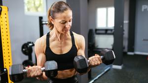 Eine Frau trainiert mit Hanteln im Fitnessstudio.