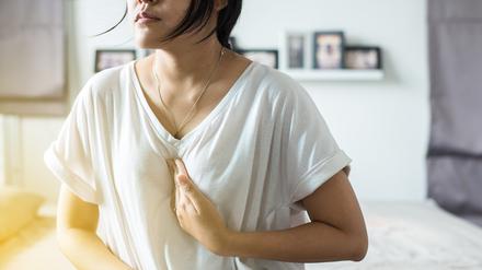 Eine junge Frau hält eine Hand ans Zwerchfell.
