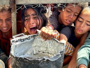 Palästinensische Kinder versuchen im Gebiet Al-Mawasi im Gazastreifen, mit ihren Töpfen Nahrungsmittel zu bekommen, die von Wohltätigkeitsorganisationen verteilt werden.