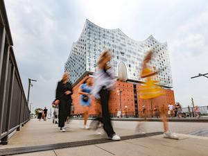 Menschen gehen vor der Elbphilharmonie in Hamburg entlang (Symbolbild).