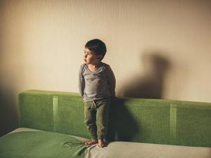 Ein Kind spielt allein auf einem Bett (Symbolbild).