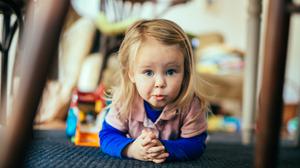 Ein knapp zwei Jahre altes Kind auf einem Teppich