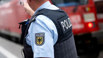 Ein Bundespolizist steht an einem Bahnsteig vor einem Zug der Deutschen Bahn.