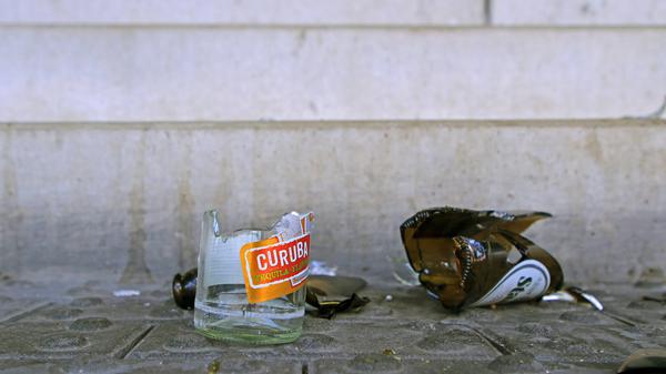 Die Scherben von zerbrochenen Glasflaschen liegen auf einem Fußweg vor einer Treppe.