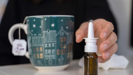 Eine Frau greift nach Nasenspray.