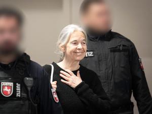 Die Angeklagte Daniela Klette reagiert zu Beginn des Verhandlungstages auf Unterstützer im Zuschauerbereich des provisorischen Gerichtssaals des Landgerichts Verden in Verden-Eitze.