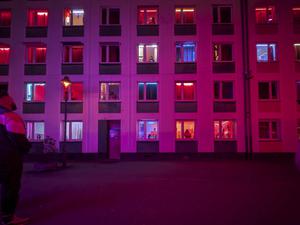 Freier vor der Fassade eines rot beleuchteten Bordells mit Prostituierten in den Fenstern in Düsseldorf.