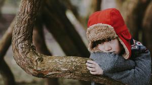 Ein kleiner Junge steht allein an einem Baum.