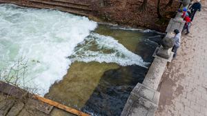 Passanten stehen an der Eisbachwelle im Englischen Garten, an der nach einer Bachreinigung nicht mehr gesurft werden kann. Die Welle ist normalerweise zu jeder Jahres- und Tageszeit ein wahrer Hotspot für Touristen und Surfer aus der ganzen Welt.