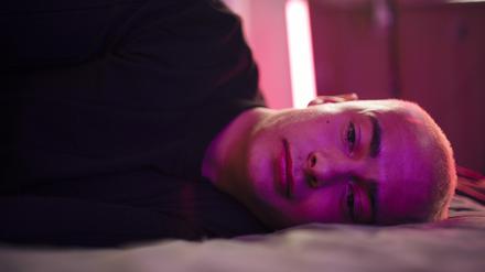 Ein traurig blickender junger Mann liegt seitlich auf einem Bett (Symbolbild).