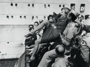 Marlene Dietrich wird von amerikanischen Soldaten auf Händen getragen.