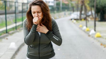 Eine Frau hustet beim Sporttreiben.