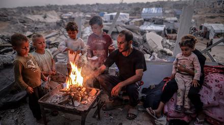 Ein Mann und einige Kinder an einem Feuer inmitten von Trümmern in Gaza.