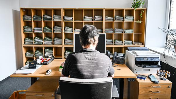 Ein Verwaltungsmitarbeiter sitzt in einem Büro am Schreibtisch.