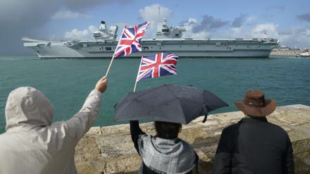 Menschen in Portsmouth stehen am Ufer und winken dem Flugzeugträger der britischen Royal Navy HMS Queen Elizabeth zu.
