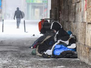 Eine Person liegt bei eisigen Temperaturen unter einer Brücke.