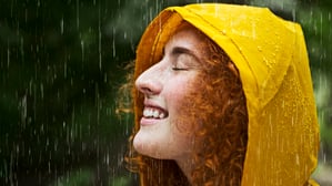 Eine fröhliche, rothaarige Frau im Regen.