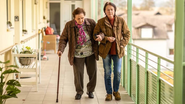 Mit der Hilfe der Tochter: Eine Seniorin ist außerhalb der eigenen vier Wände mit Unterstützung unterwegs.
