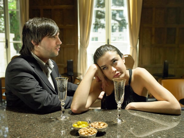 Ein gelangweilt wirkendes Paar mit leeren Sektgläsern (Symbolbild).