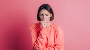 Illustration: Eine Frau hustet in ihre Hand.